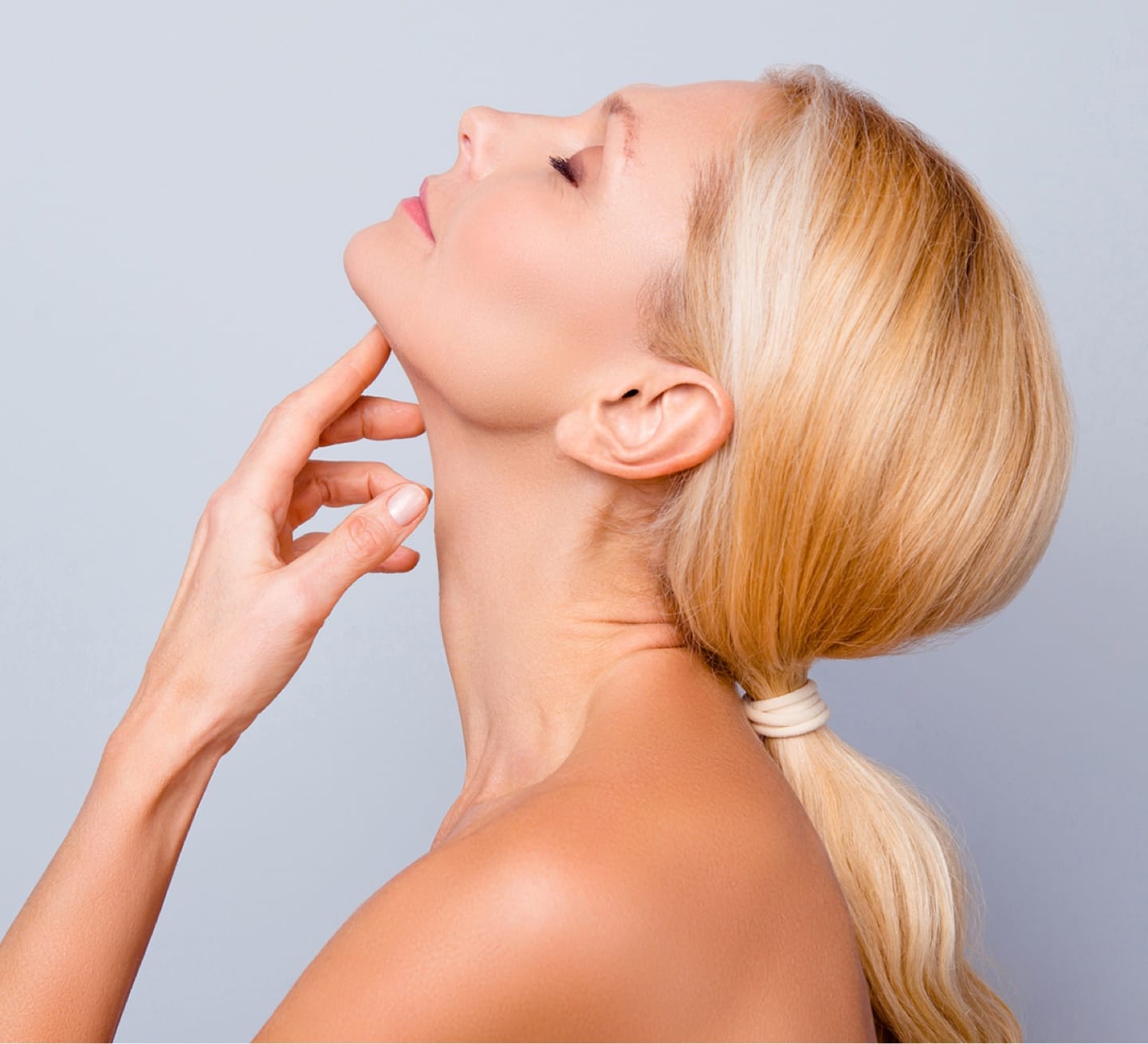 Woman with a finger to her upturned chin highlighting a neck lift in Denver