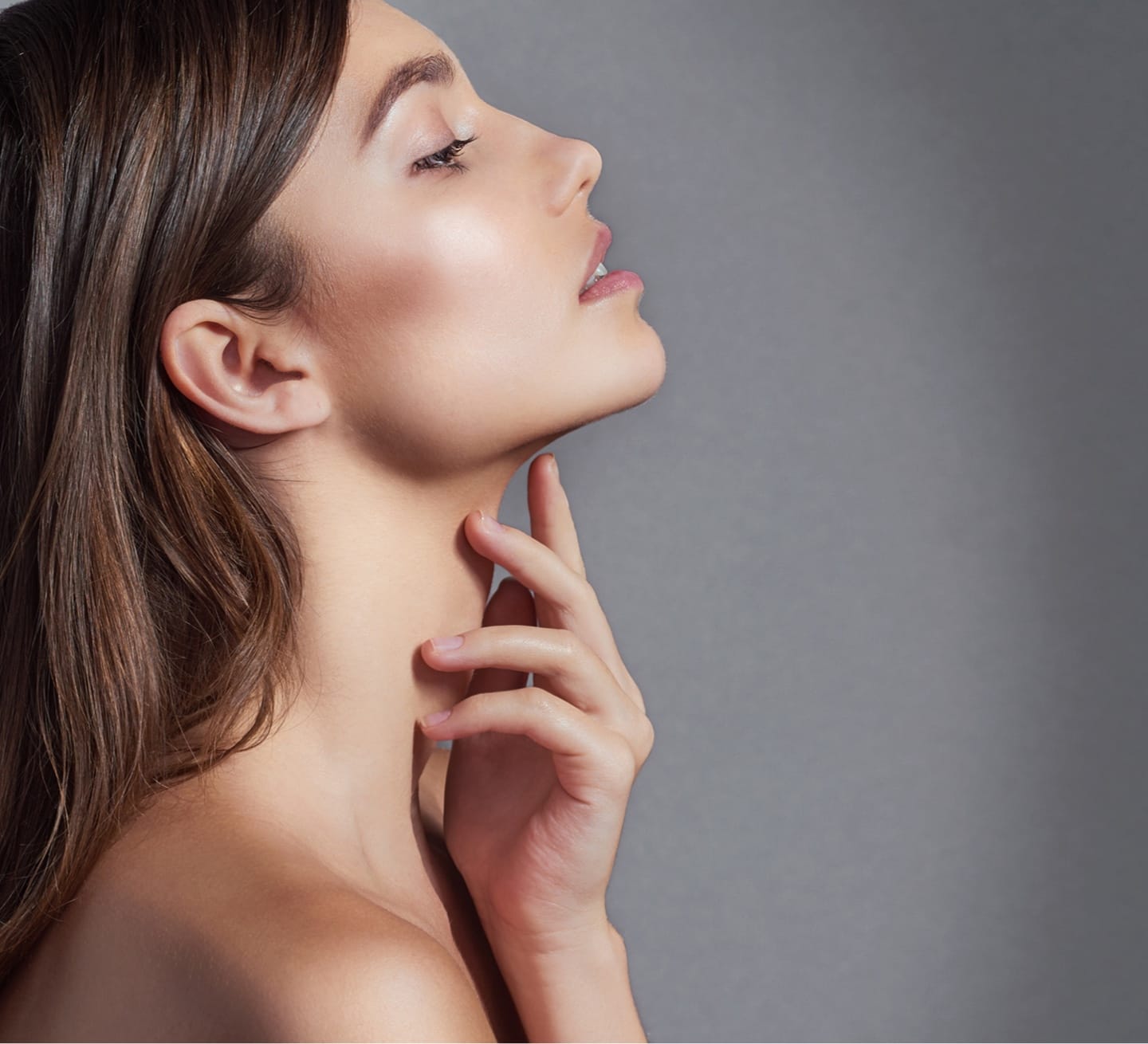 Woman with her hand against her neck, her chin pointing up